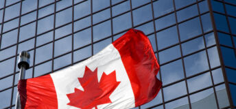 Canadian flag in front of modern building.