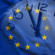 Lawmakers extend EU Taxonomy scrutiny period by two months Double exposure of clock and blue flag of European Union