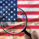 A magnifying glass focusing on American bills and flag