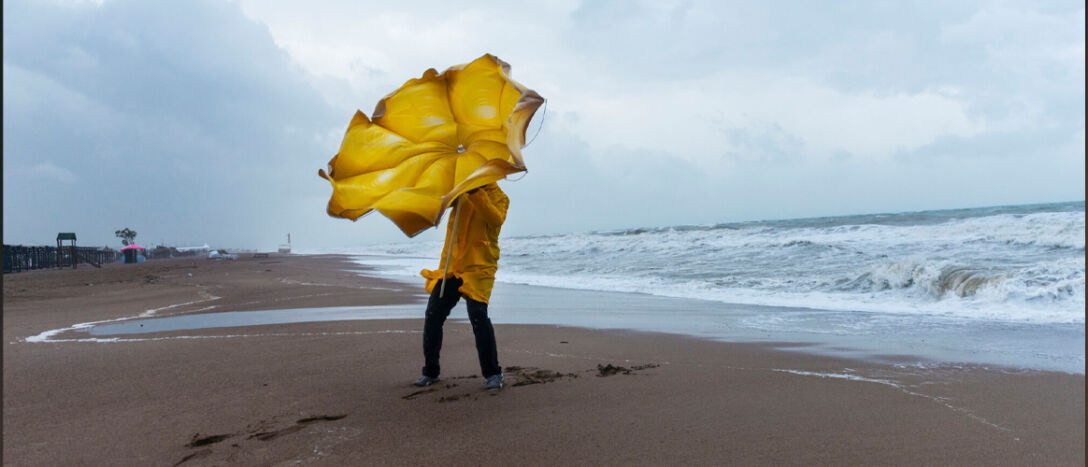 Person on a beach trying to hold an umbrella on a windy day