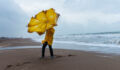 Person on a beach trying to hold an umbrella on a windy day