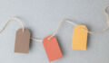 Autumn color palette, blank gift tags with jute twine string on a gray textured surface with copy space.